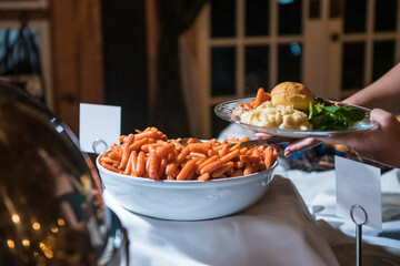 Closeup shot of small carrots in the bowl and a hand put another delicious dish on the table