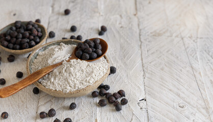 Bowl of black chickpea flour and beans with a wooden spoon closeup