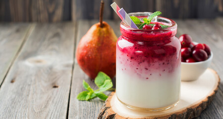 Healthy breakfast. Fresh cranberry smoothie in a glass jar on the old wooden background. Selective focus.