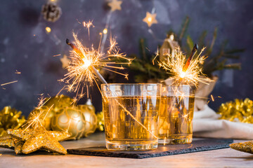 Burning sparklers in glasses with cocktails on the Christmas table. Gold palette
