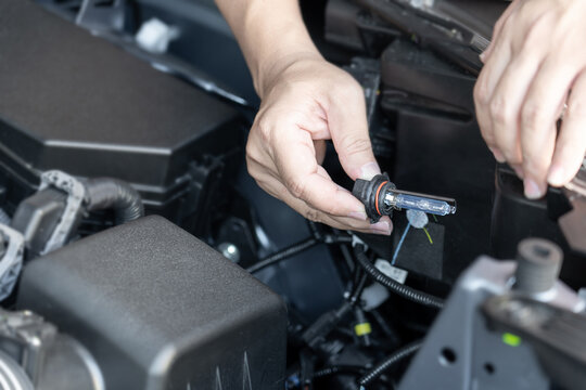 A man hold Xenon car headlights and and inserted into the headlight to replace the broken bulb in engine room : Replacing the headlight bulbs of the car itself service concept