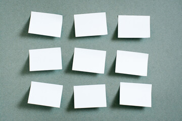 Blank small sheets of paper are arranged in rows on the green background. Green concept. Reminders and goals. Top view