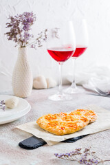 Two heart shaped pizzas on paper on a set table for valentine's day celebration. Vertical view