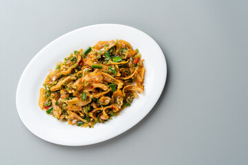 Fried anchovy cooked with green chili or ikan teri cabe ijo is a traditional food from west sumatra, Indonesia. served on white plate and isolated on gray background.