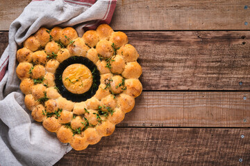 Roasted camembert cheese and homemade bread heart shaped and thyme on rustic background. French cheese. Concept of romantic love for Valentines Day. Top view, copy space.