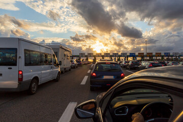 Cars lined up at the toll booths on the outskirts of Rome at sunset.