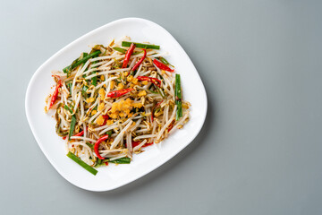 Tumis Tauge ikan asin or Salted Bean Sprouts is one of type traditional cuisine in Indonesia. sauteed bean sprouts cooked with salted fish served on plate and isolated gray background.