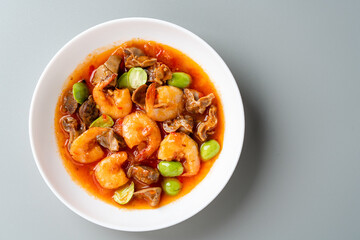 Chili prawns or Sambal Udang with petai or pete in white plate on gray background. Indonesia cuisine food. 