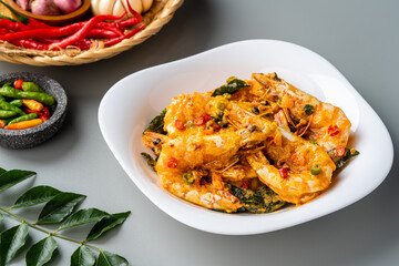 udang saus telur asin or Salted egg fried shrimp with curry leaves served on white plate and isolated on gray background.
