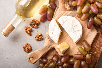 Two Wine bottles with grapes, slice cheese camembert, nut and wineglasses on old gray concrete table background with copy space. Red wine with a vine branch. Wine composition. Mock up.