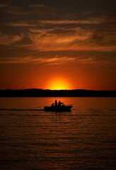 Obraz premium Silhouette Passenger Motor Boat Sailing at Sunset