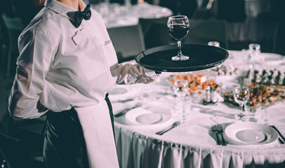 Waiter holding tray with red wine glass