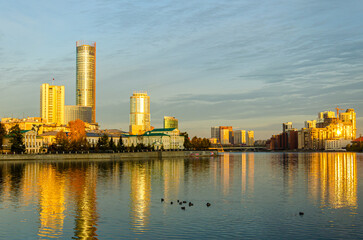 Obraz na płótnie Canvas High-rise buildings on the shore of the lake at dawn.