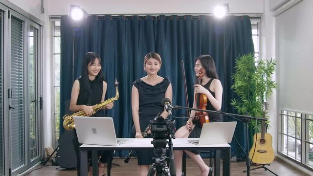 Beautiful Female musician playing instrumental oboe saxophone violin flute guitar use laptop computer singing online streaming broadcast teaching tutorial webcam live show
