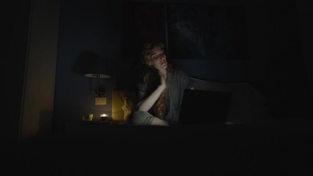 Student studying late at night in her bed at home, the woman is tired from a long day of work