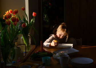 Fototapeta na wymiar A girl with lemon and a tulip on the windowsill in a narrow strip of light of the setting sun