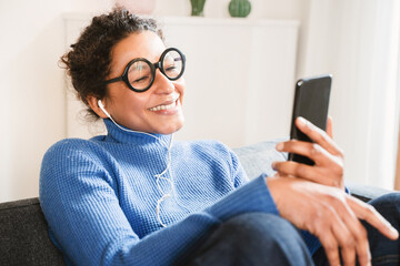 Fototapeta na wymiar Cheerful black woman listening to music using smartphone