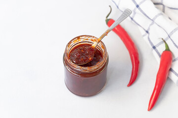 Above view of jar with sweet spicy jam made from chili pepper on neutral grey background with copy...