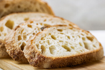 Close up of slices of baked wheat bread on wooden board, selective focus.