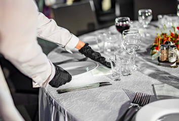 Waitress hand in gloves puts the plate, table setting