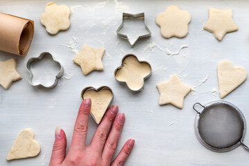 Top view of woman hands cooking a gingerbread cookie in the form of heart, star, cloud and flower. Christmas and New Year concept, festive preparations for winter hilodays
