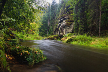 Fototapeta premium Mystischer Fluss umgeben von Felsen in herbstlichem Nebel.