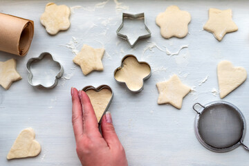 Top view of woman hands cooking a gingerbread cookie in the form of heart, star, cloud and flower. Christmas and New Year concept, festive preparations for winter hilodays

