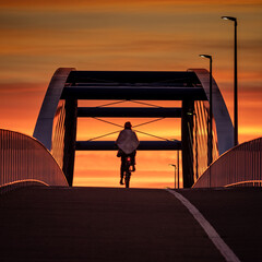 Back view of a cyclist on the bridge at sunset