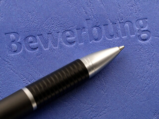 job application in german with ballpoint pen, close up of a blue application folder
