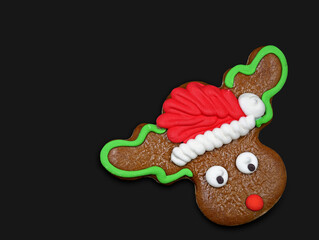 Christmas reindeer cookie, rudolph with santa hat gingerbread isolated on black background with...