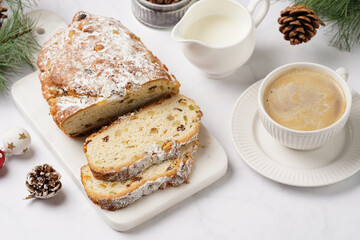 White porcelain cup with coffee cappuccino on a white saucer plate and christmas pastry stollen on a marble table