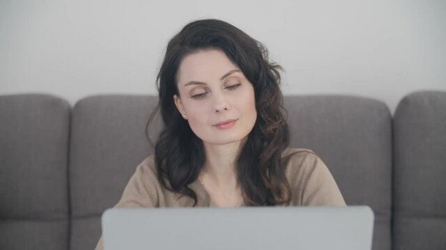Freelance worker woman reading messages online in laptop computer. Freelancer working from home on lockdown. Stock video clip of beautiful white female model in  30s using notebook pc in her apartment