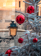 An old street lantern in Colmar and a Christmas tree decorated with red balloons