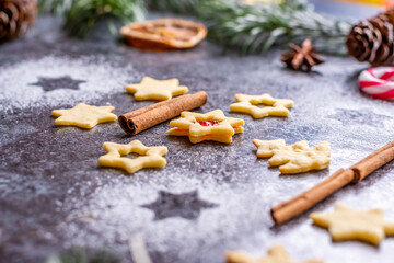Christmas sweets and cookies in form of christmas tree placed on gray desk with pine cone and branch on the side. Winter and christmas decorations, cinnamon, sugar and star anise.