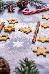 Christmas sweets and cookies in form of christmas tree placed on gray desk with pine cone and branch on the side. Winter and christmas decorations, cinnamon, sugar and star anise.
