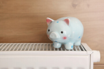 Pig piggy bank on a radiator indoors close-up. Heating concept.