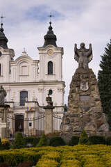 Obraz premium Monument next to the church surrounded by trees and alleys.
