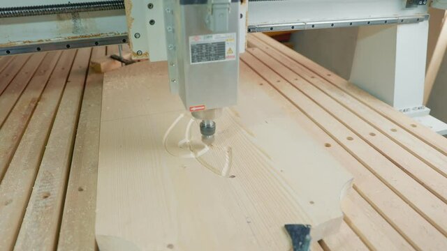 CNC machine cuts figures on a wooden blank close-up