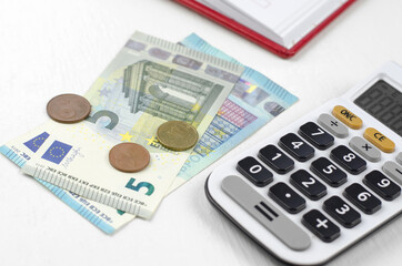 Calculator and euro money on a white table. Money and cash savings concept