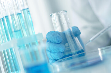 Scientist holds a flask with reagents in the laboratory, selective focus. Development of a vaccine...