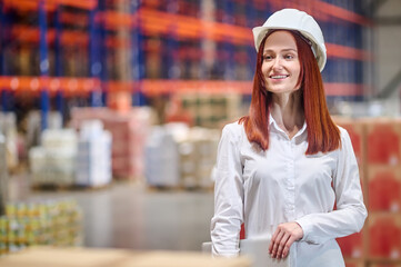 Determined woman in helmet with laptop at warehouse