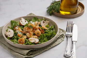 Arugula salad with shrimp and champignons, olive oil and dill on a wooden board on a white surface