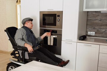 Man with disability checking timer of electric oven while cooking food for himself in the kitchen