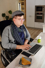 Fototapeta na wymiar Serious young man concentrating on remote work while sitting by table in front of laptop in home environment