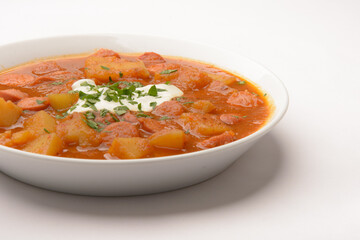 homemade dish so-called Erdapfelgulsch on a white plate with white background