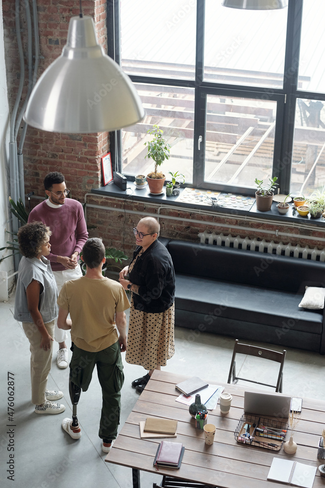 Poster Young confident colleagues discussing working points at meeting while standing against large window in openspace office