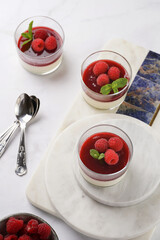 Italian dairy dessert panna cotta with raspberry jam and fresh raspberries on marble board