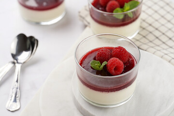 Italian dairy dessert panna cotta with raspberry jam and fresh raspberries on marble board