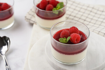Italian dairy dessert panna cotta with raspberry jam and fresh raspberries on marble board