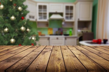 Wooden tabletop with a blurred kitchen with Christmas tree. Background for display or montage your products.